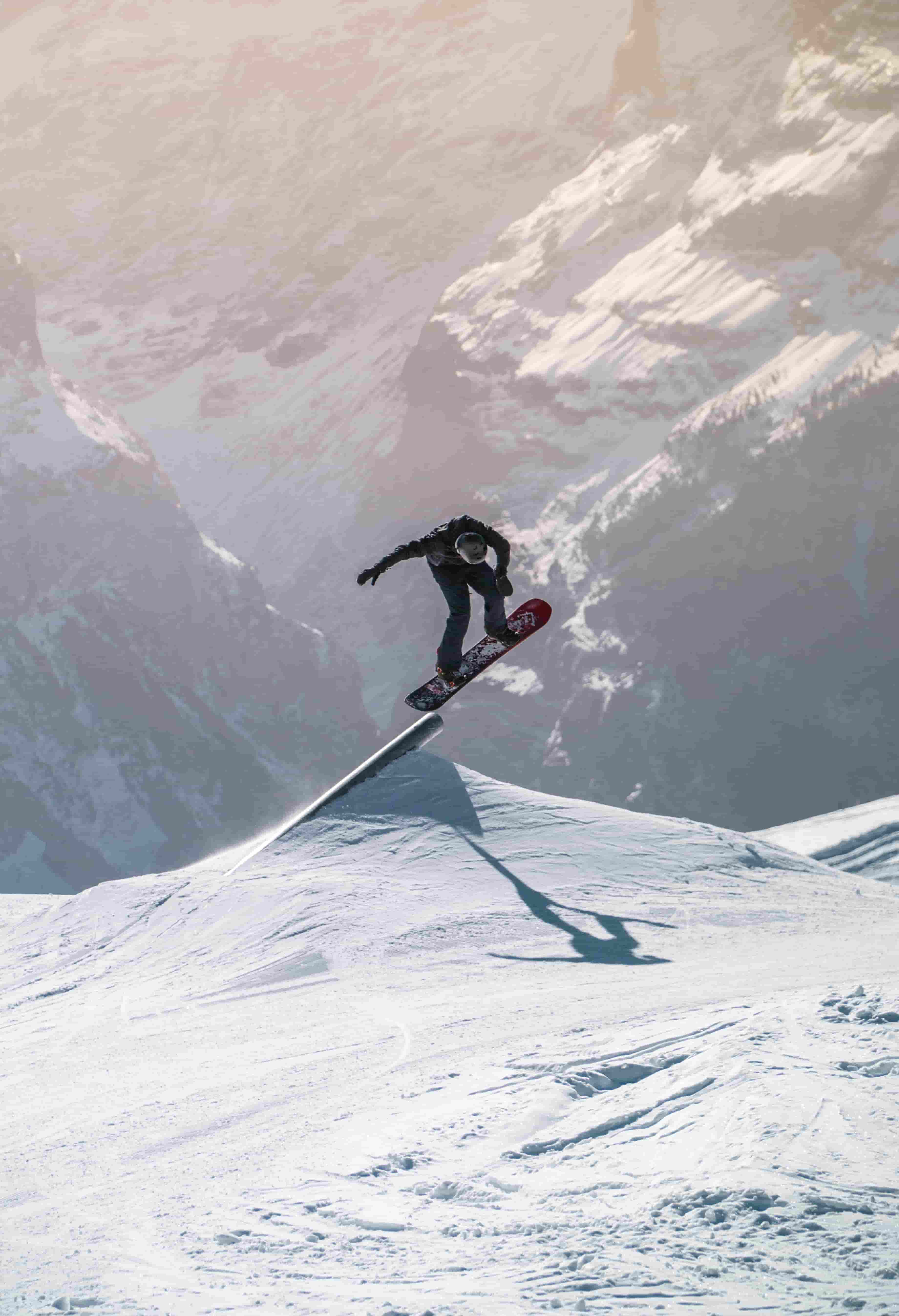Snowboarder fährt über eine Kante und trägt eine Ski-Sonnenbrille